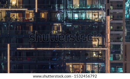 Lights in windows of modern multiple story building in urban setting at night timelapse. Glowing lights in residential skyscraper in Dubai Marina