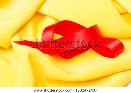 Red bow, on a yellow cloth background, ribbon to make bows and decorate gifts.