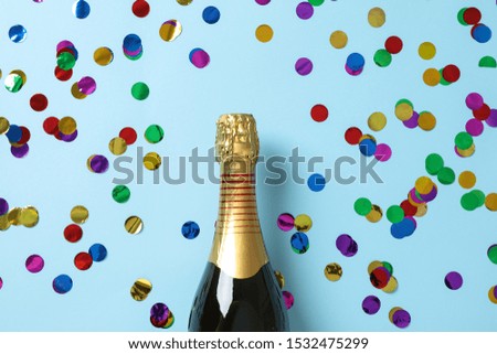 Champagne bottle and glitter on blue background, space for text