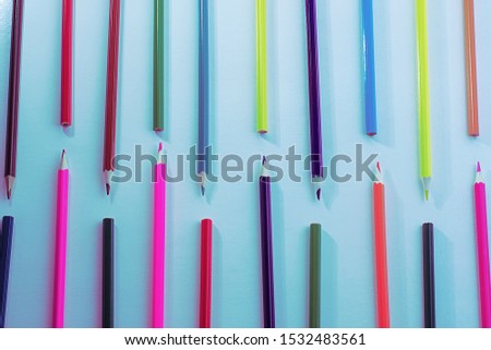 A pattern of wooden color pencils in neon light. Minimal beauty concept. Copy space concept back to school, learning process, study at school, drawing