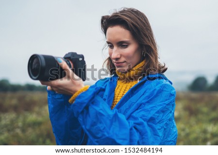 photographer tourist girl in blue raincoat hold in hands photo camera take photography foggy mountain