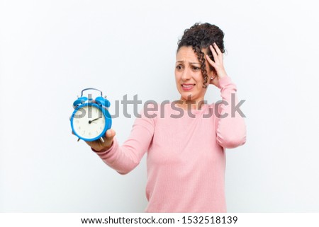 young pretty woman with an alarm clock against white wall