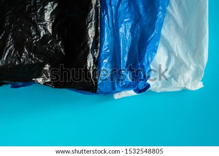Black, blue and white plastic bags on blue background representing the concept about plastic pollution 