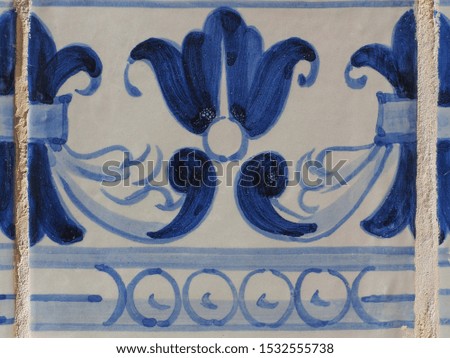 Vintage, glazed, ceramic wall tile, with painted blue flower, close up. Azulejo floral ornate pattern, for design or backdrop. Abstract old tiles background. Traditional ornamental Portuguese art form