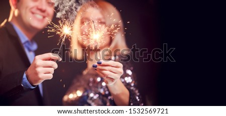 Picture of smiling couple with sparklers on black background