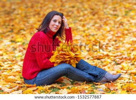 Young pretty woman walking in an autumn fall park with colourful maple trees