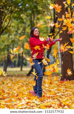 Young pretty woman walking in an autumn fall park with colourful maple trees