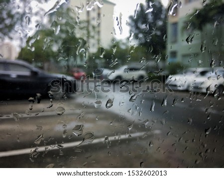 Rain drops on the windshield, background blurred view of car park, window car on the rainy day.