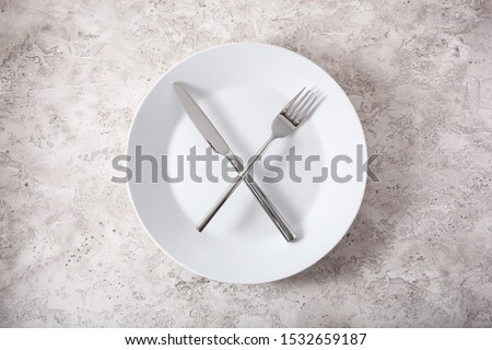 concept of intermittent fasting and ketogenic diet, weight loss. fork and knife crossed on a plate Royalty-Free Stock Photo #1532659187