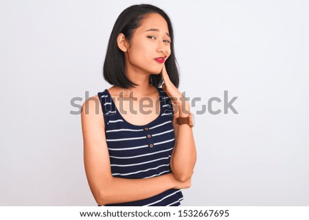 Young chinese woman wearing striped t-shirt standing over isolated white background touching mouth with hand with painful expression because of toothache or dental illness on teeth. Dentist concept.