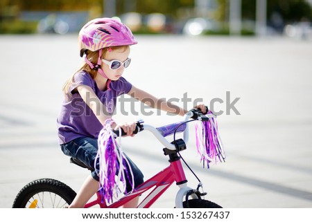 Adorable girl riding a bike on beautiful summer day