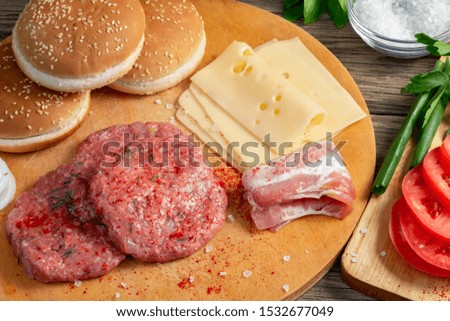 Process of cooking homemade burgers, meatballs, tomatoes, cheese and other ingredients on a wooden background, close up