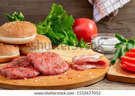Process of cooking homemade burgers, meatballs, tomatoes, cheese and other ingredients on a wooden background