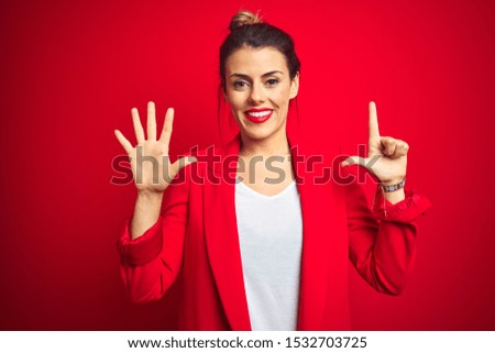 Young beautiful business woman standing over red isolated background showing and pointing up with fingers number seven while smiling confident and happy.
