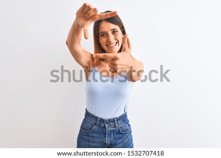Beautiful redhead woman standing over isolated background smiling making frame with hands and fingers with happy face. Creativity and photography concept.