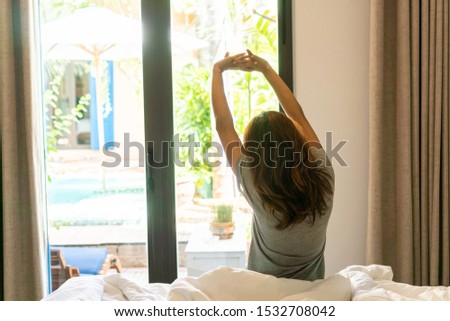 Easy lifestyle Asian woman waking up in weekend morning taking some rest relaxing in hotel room enjoying world lazy day, having happy life quality balance concept