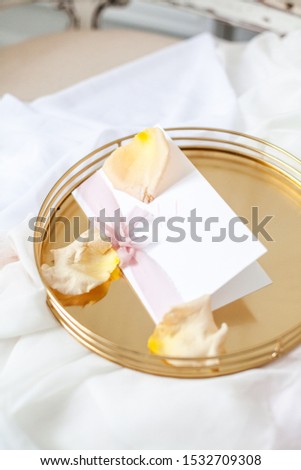 Wedding invitation on a gold tray with flowers.
