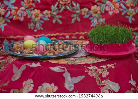There are colored eggs, hazelnuts, dates, and peanuts in the cabin. Novruz symbol on xoncha on white background Azerbaijan holiday . Green semeni .