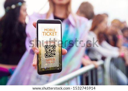 Close Up Of Woman Holding Mobile Ticket On Screen To Camera As She Arrives At Entrance To Music Festival Royalty-Free Stock Photo #1532745914
