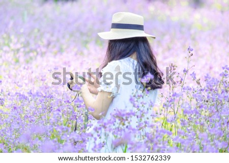 Photographer tourist make photo on camera. Girl in hat with dresses travels in Romantic trip to beautiful purple flower field.