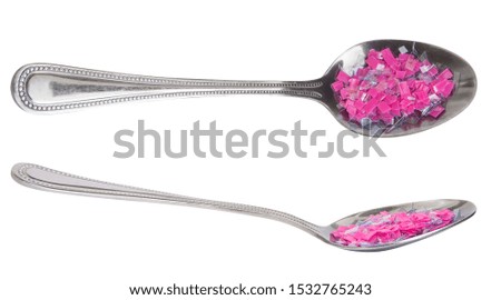 Pieces of transparent and pink plastic on the spoon. Garbage refuse for lunch. Waste recycling and pollution concept