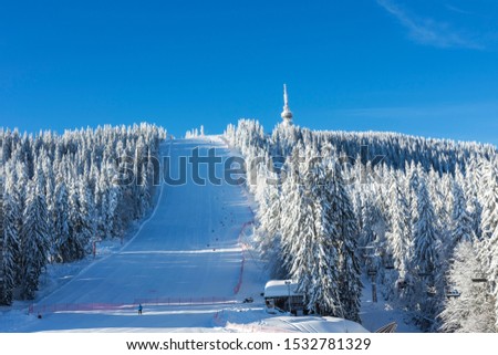Calm beautiful morning in ski resort Pamporovo. Man is watching the white snowy slope near Snejanka TV tower.  Sports and recreation concept. Selective focus. Royalty-Free Stock Photo #1532781329