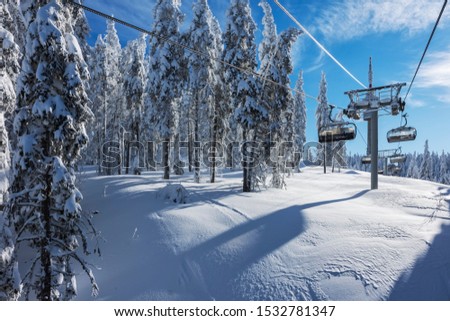 Sunny morning in the Rhodope Mountains, ski resort Pamporovo. Chair ski lift over pine trees. Snejanka TV tower in  background. Sports and recreation concept.Selective focus. Royalty-Free Stock Photo #1532781347