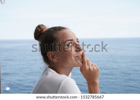 
beautiful girl in white portrait on a background of the ocean. girl emotions cunning, playfulness, secret sign, silence sign.
