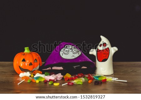 Halloween decorations and treats on top of a wooden table against a black background
