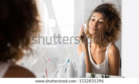 Skincare Routine. African American Girl Removing Makeup Using Cotton Pad Looking In Mirror Standing In Bathroom. Panorama Royalty-Free Stock Photo #1532831396