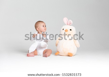 Baby girl boy in wgite studio with toy chicken