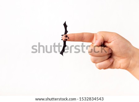 Woman playing with Halloween paper bat on finger, white background, copy space