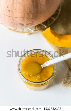 Jar dessert. Couscous with pumpkin-apple-cinnamon sauce in jar on white kitchen.