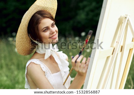 young woman with a brush in her hand draws a picture