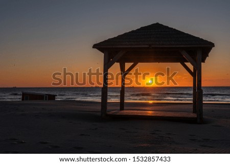 Silhouete of gazebo on the sea beach in beautiful sunset with serene sea in the background