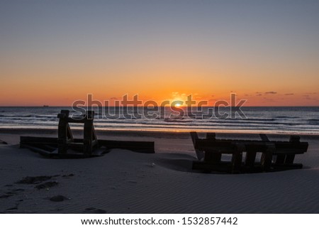 Silhouete of metal construction design like stool on the sea beach in beautiful sunset with serene sea in the background