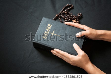 Christian Bible and rosary on a black surface. Orthodox Bible. Translation – Bible