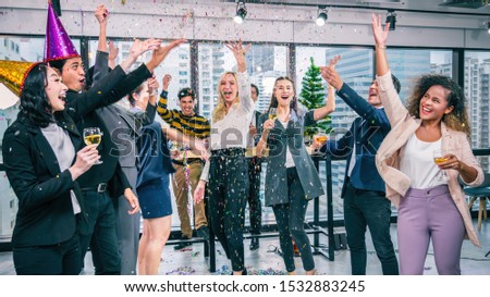 Group of business people celebrate the new year by drinking champagne, DJ playing music for everyone to dance before the holidays.