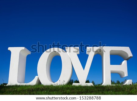 White letters forming word LOVE standing on green grass