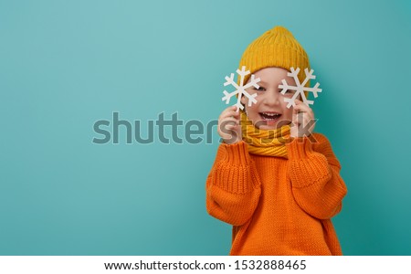 Winter portrait of happy child wearing knitted hat, snood and sweater. Girl having fun, playing and laughing on teal background. Fashion concept.                                Royalty-Free Stock Photo #1532888465