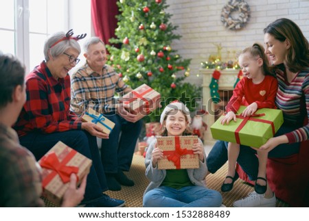 Merry Christmas and Happy Holidays! Grandma, grandpa, mum, dad and children exchanging gifts. Parents and daughters having fun near tree indoors. Loving family with presents in room.