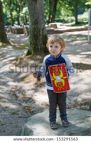 Happy little toddler boy with knight armor, outdoors