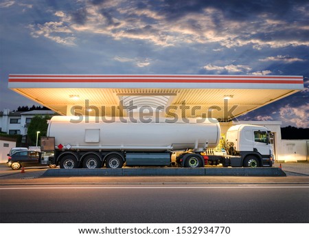 Tanker gas truck delivering fuel at service station against dramatic night sky Royalty-Free Stock Photo #1532934770