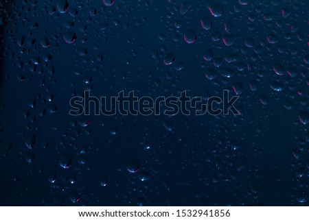 Raindrops on the surface of window panes Natural pattern of raindrops, on a blue background.