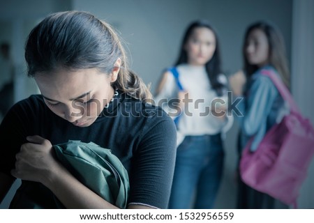 Picture of depressed teenage girl bullied with her friends in the classroom Royalty-Free Stock Photo #1532956559