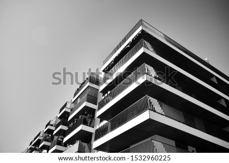 Fragment of a facade of a building with windows and balconies. Modern home with many flats. Black and white.
