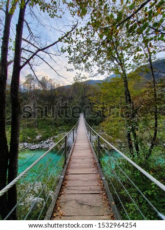 Bridge over river Soca in Soca valley Kobarid Slovenia. Orange. blue and green colors. Pedestrian bridge made out of wood. Picture was taken on 13th of October 2019.