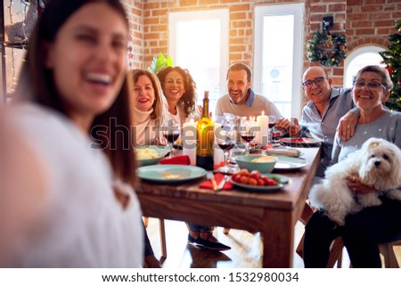 Family and friends dining at home celebrating christmas eve with traditional food and decoration, taking a selfie picture together