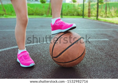  Children's feet and a basketball ball close-up. Healthy lifestyle and sport concepts.