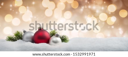 Christmas balls and fir branches in the snow with a sparkling golden background 